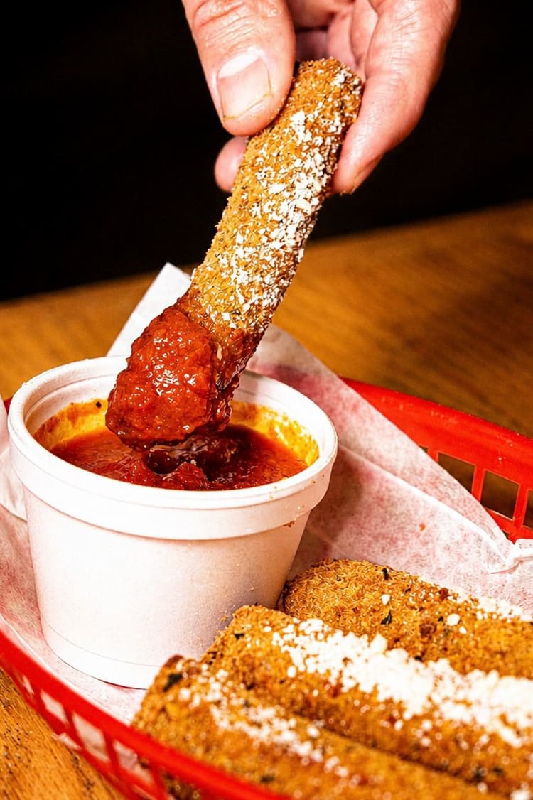A mozzarella stick dipped in marinara