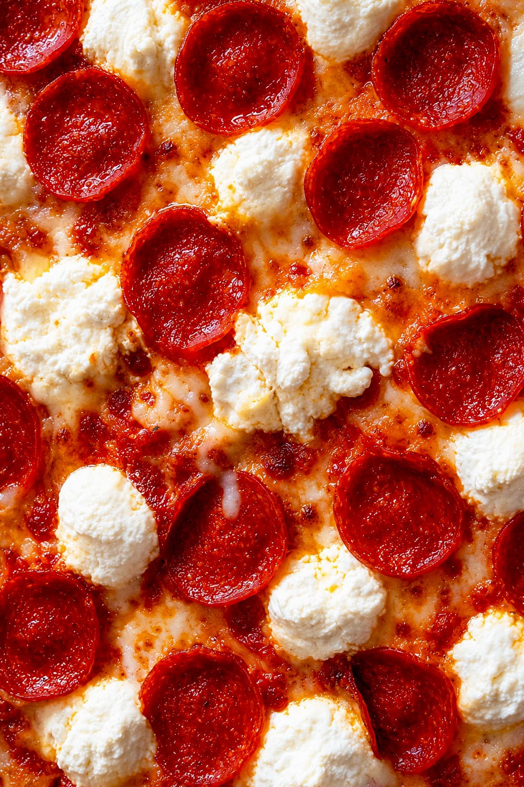Close-up of a pepperoni pizza with dollops of ricotta