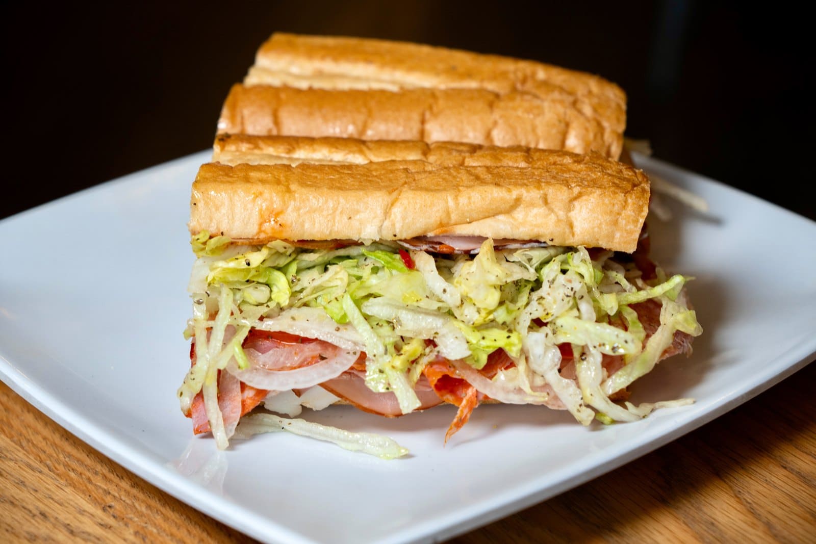 A sub piled with lettuce, on a plate